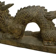 Eine dunkle Steindrachenskulptur mit geöffnetem Maul, die auf einem rechteckigen Sockel liegt.