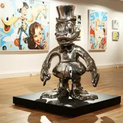 Glänzende Pop-Art-Skulptur einer Comicfigur mit Zylinder in einer Galerie, im Hintergrund bunte Gemälde.