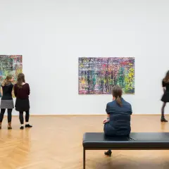Besucher betrachten abstrakte Gemälde. Eine Liste der Künstler hängt nicht aus, aber die Werke sprechen für sich.