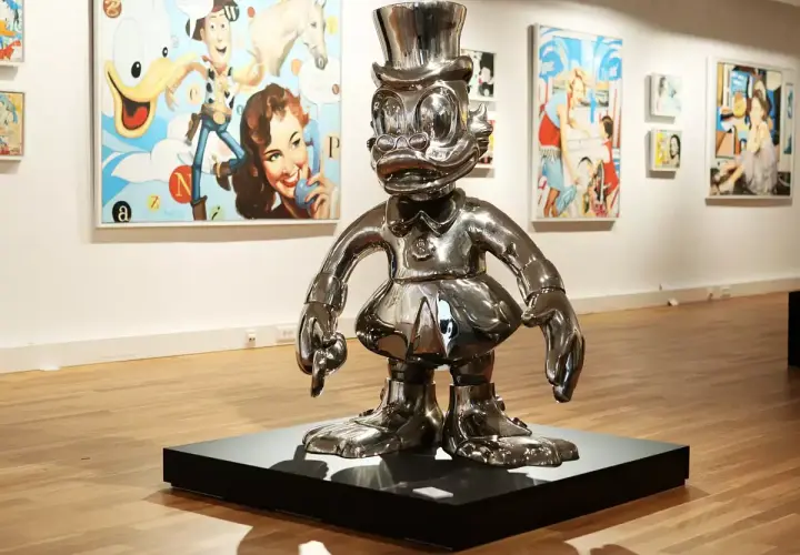 Glänzende Pop-Art-Skulptur einer Comicfigur mit Zylinder in einer Galerie, im Hintergrund bunte Gemälde.
