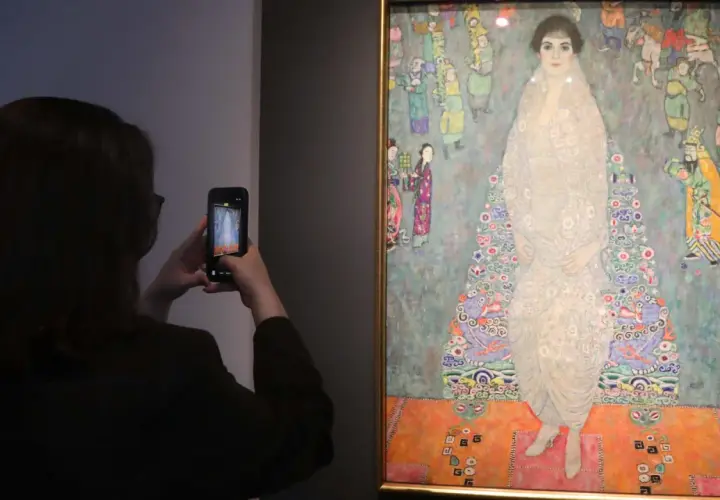 Besucherin fotografiert das größte Gemälde der Welt, ein detailreiches Porträt einer Frau in einem opulenten Kleid, umgeben von bunten Figuren.