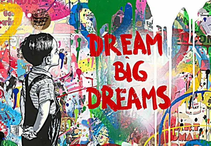 Graffiti mit Kind und den Worten "DREAM BIG DREAMS" vor bunter, spritziger Wand.