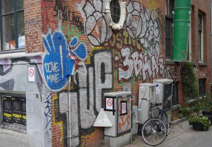 Ziegelwand mit Graffiti, Fahrrad und grauen Kästen.