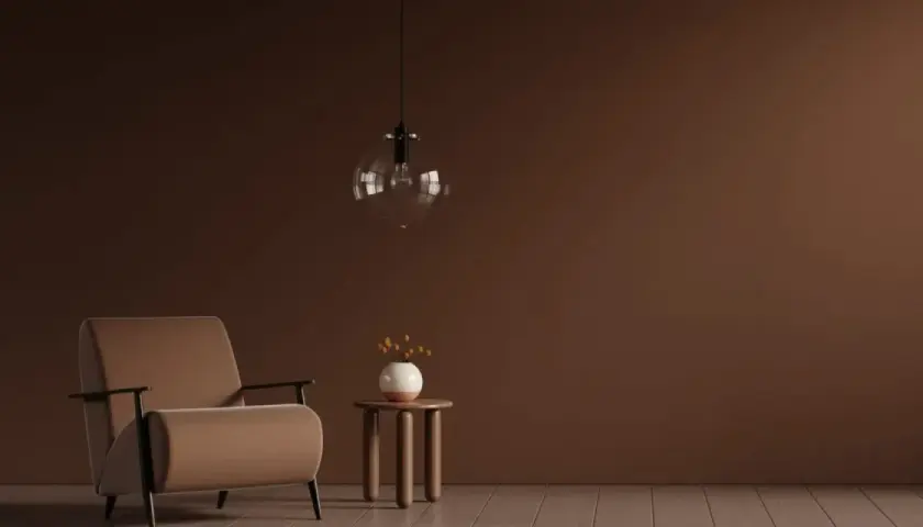 Ein Sessel in warmem Braun steht neben einem kleinen Beistelltisch mit einer Vase. Die Wand und der Boden sind in verschiedenen Brauntönen gehalten, die sich harmonisch mischen.