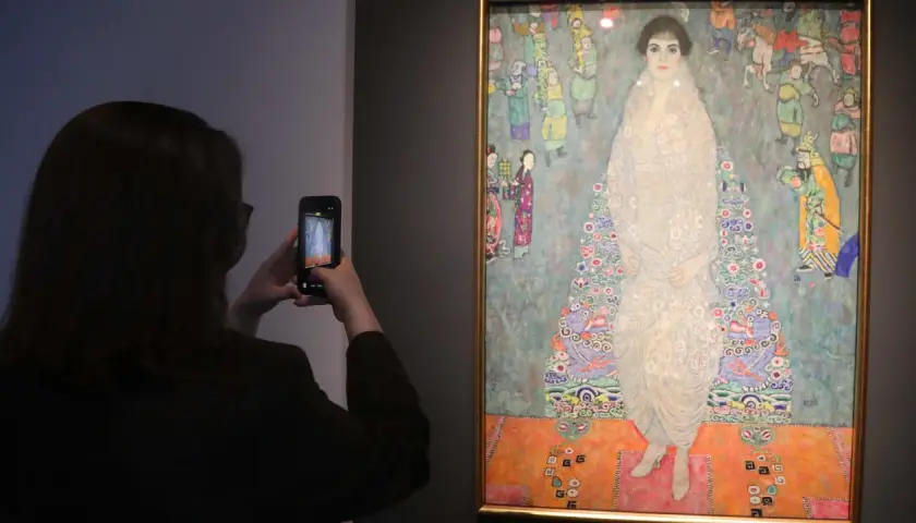 Besucherin fotografiert das größte Gemälde der Welt, ein detailreiches Porträt einer Frau in einem opulenten Kleid, umgeben von bunten Figuren.