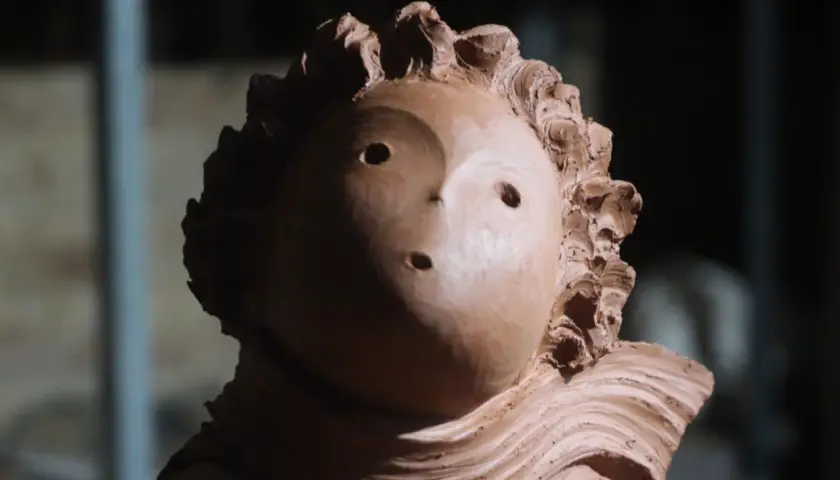 Ton-Skulptur eines Kopfes mit welligem Haar und zwei Augenlöchern.
