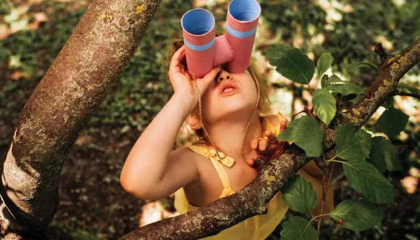 Ein junger Mann mit selbstgebasteltem Fernglas erkundet den Wald.