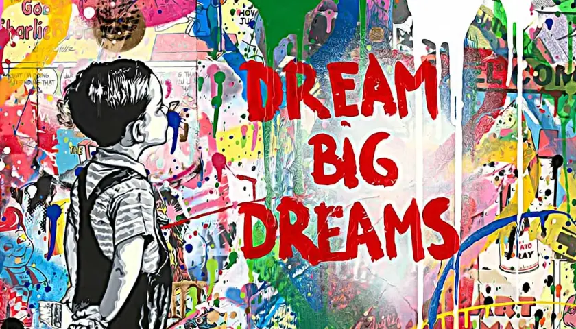 Graffiti mit Kind und den Worten "DREAM BIG DREAMS" vor bunter, spritziger Wand.