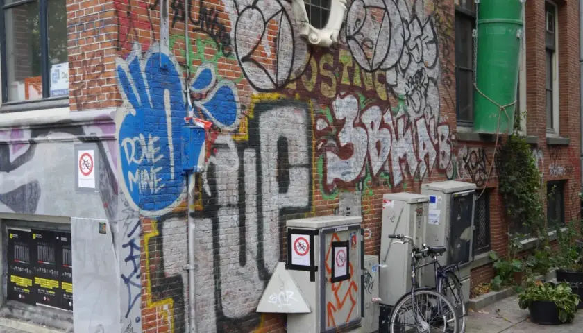 Ziegelwand mit Graffiti, Fahrrad und grauen Kästen.