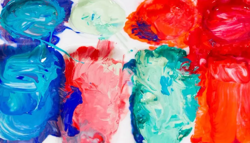 Farben auf einer Palette, bereit zum türkis mischen. Blau, Rot und Grün vermischen sich zu lebendigen Farbtönen.