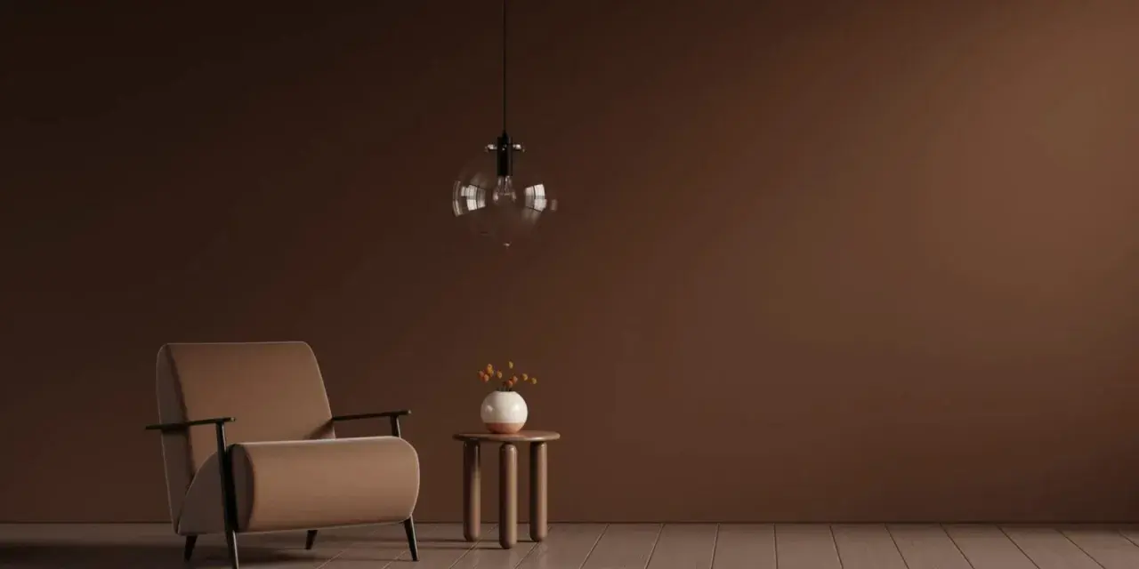 Ein Sessel in warmem Braun steht neben einem kleinen Beistelltisch mit einer Vase. Die Wand und der Boden sind in verschiedenen Brauntönen gehalten, die sich harmonisch mischen.