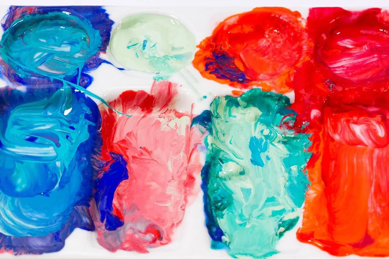 Farben auf einer Palette, bereit zum türkis mischen. Blau, Rot und Grün vermischen sich zu lebendigen Farbtönen.