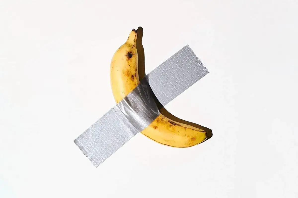 Eine Banane, mit Klebeband an einer weißen Wand befestigt, ist ein provokantes Beispiel für Konzeptkunst.