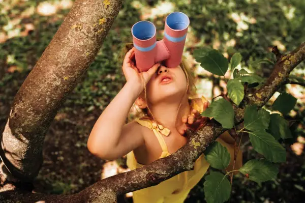 Ein junger Mann mit selbstgebasteltem Fernglas erkundet den Wald.